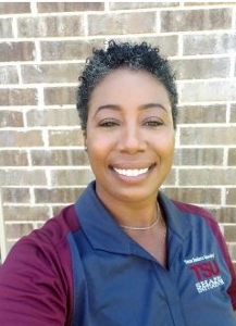 Woman with short hair, brown skin, maroon and gray shirt.
